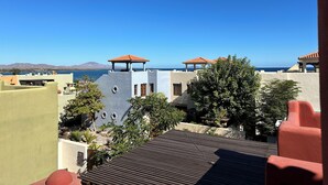 A coastal view with buildings, a clear sky, and a distant mountain range. - Beautiful 2 Bed, 2 Bath Casa Steps From The Beach & Pools In Loreto Bay (Loreto)
