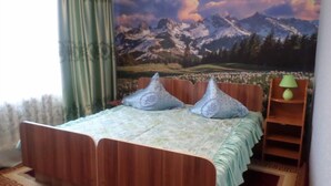 A bedroom with a bed, two pillows, a nightstand, and a lamp. - Vacation House - Hostel (Kochkor)