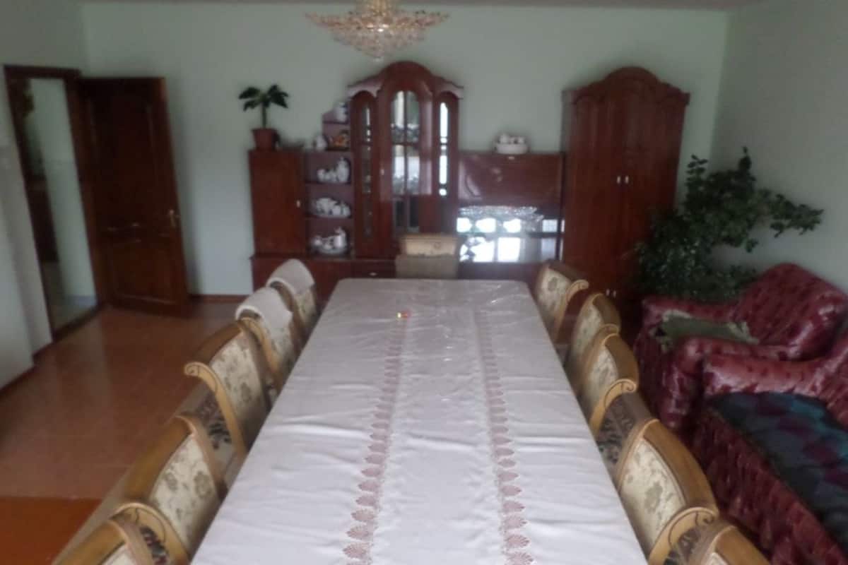 A dining room with a long table, ornate chairs, and a chandelier.