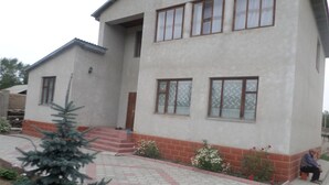 A two-story building with a flat roof, rectangular windows, and a brick base. - Vacation House - Hostel (Kochkor)