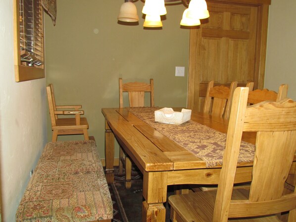 A wooden dining table with chairs, a bench, and a patterned runner.