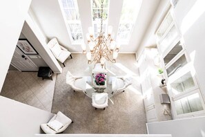 Amplia habitación con candelabro, una mesa de comedor y vistas al exterior a través de amplias ventanas.