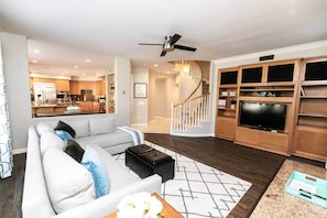 A modern living room with a sofa, coffee table, and a TV on a wooden cabinet. - Luxurious Home w/Hot Tub & Pool + Water Slide (San Diego)