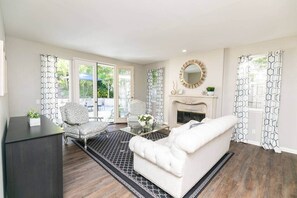A living room with a fireplace, patterned curtains, and a white sofa.