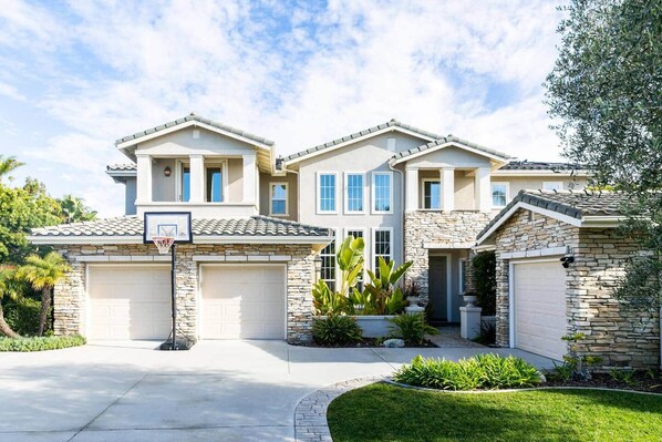 A two-story house with a stone facade, a garage, and a basketball hoop.