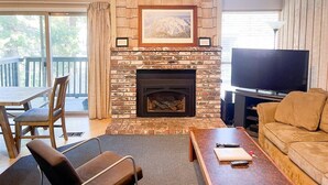 A living room with a stone fireplace, a television, and a sofa.