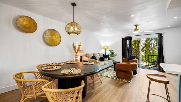 Uma área de jantar moderna com uma mesa redonda, cadeiras de vime e um sofá.