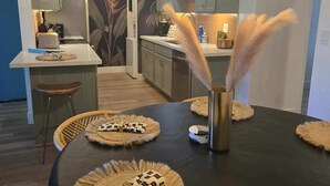 Cozinha moderna com armários cinza, ilha central e luminária pendente decorativa.