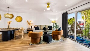 Uma sala de estar moderna com um sofá, duas poltronas, uma mesa de centro e um espaço de refeições com uma mesa e cadeiras.