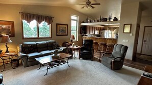 A living room with a sofa, coffee table, and chairs, a dining area with a table and chairs, and a kitchen with cabinets and appliances. - Beautiful Black Hills Home just minutes from so many attractions.  (Custer)
