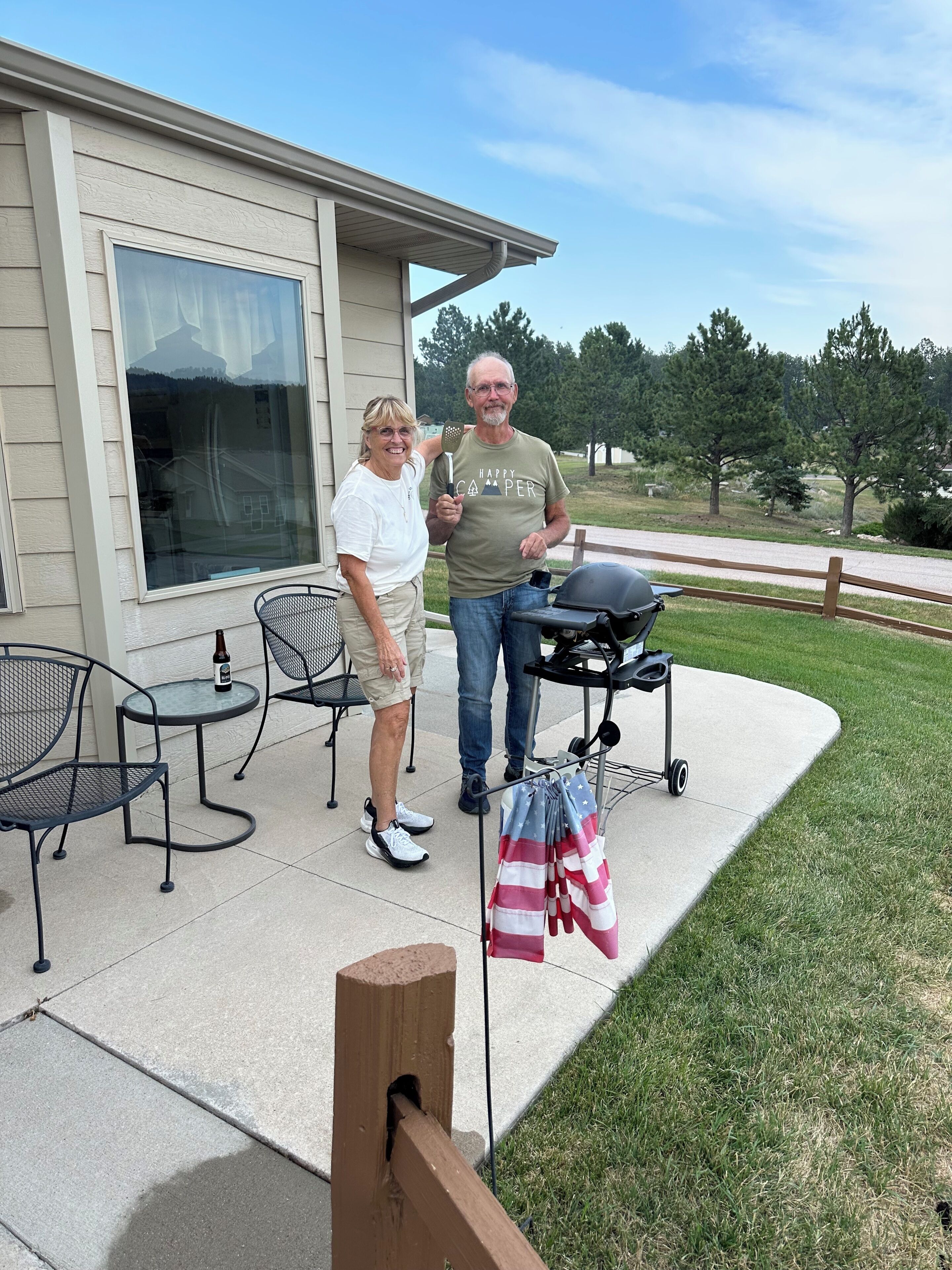 A patio with outdoor furniture, a barbecue grill, and a flag.