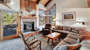 Ein gemütliches Wohnzimmer mit Kamin, großen Fenstern und bequemen Sitzmöglichkeiten.