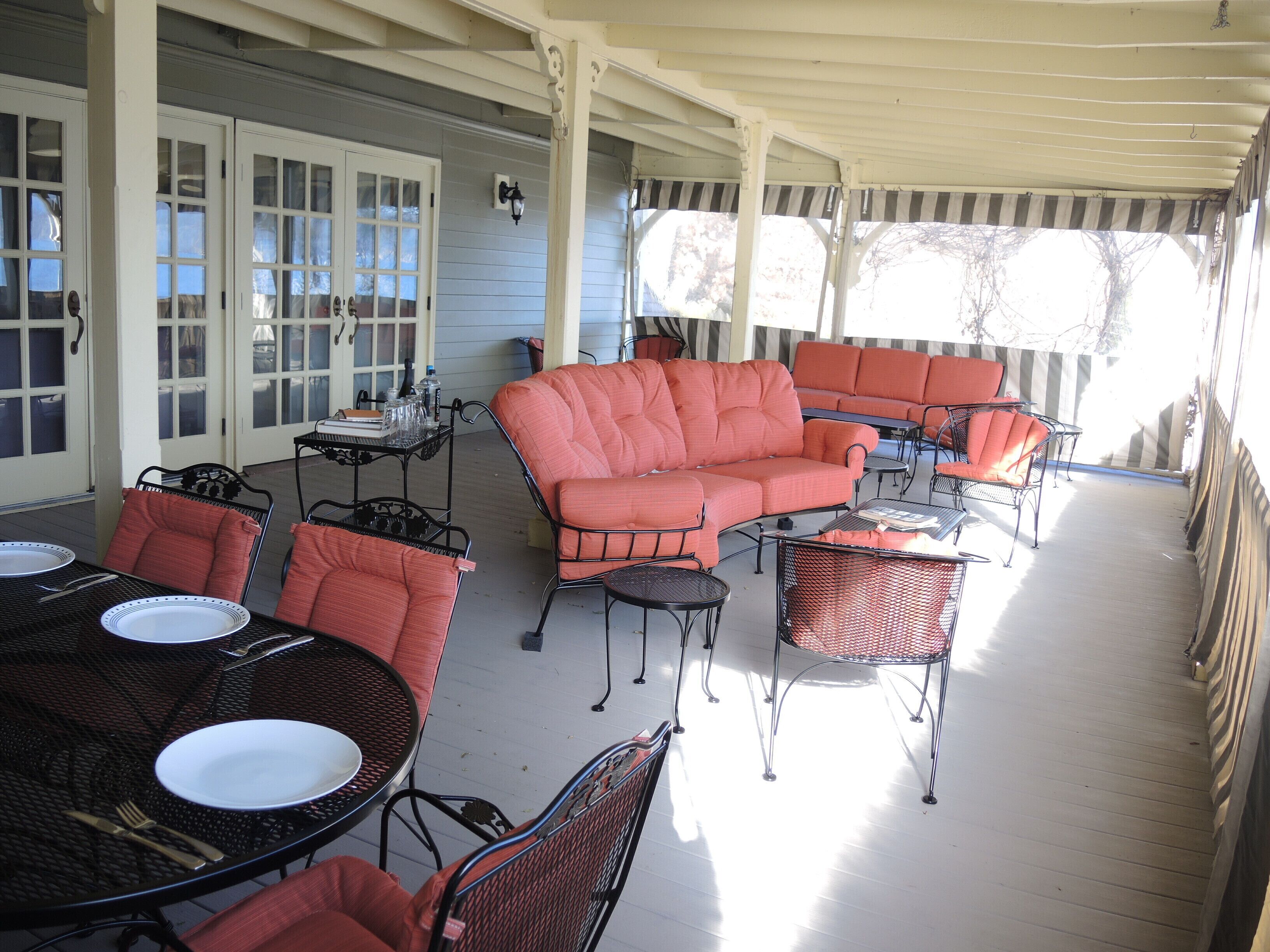 A covered outdoor patio with a sectional sofa, dining table, and chairs.