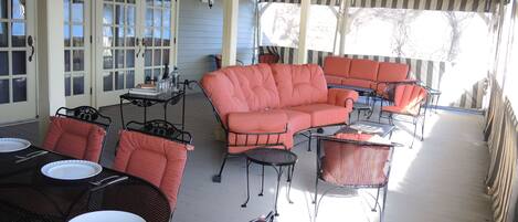 A covered outdoor patio with a sectional sofa, dining table, and chairs.
