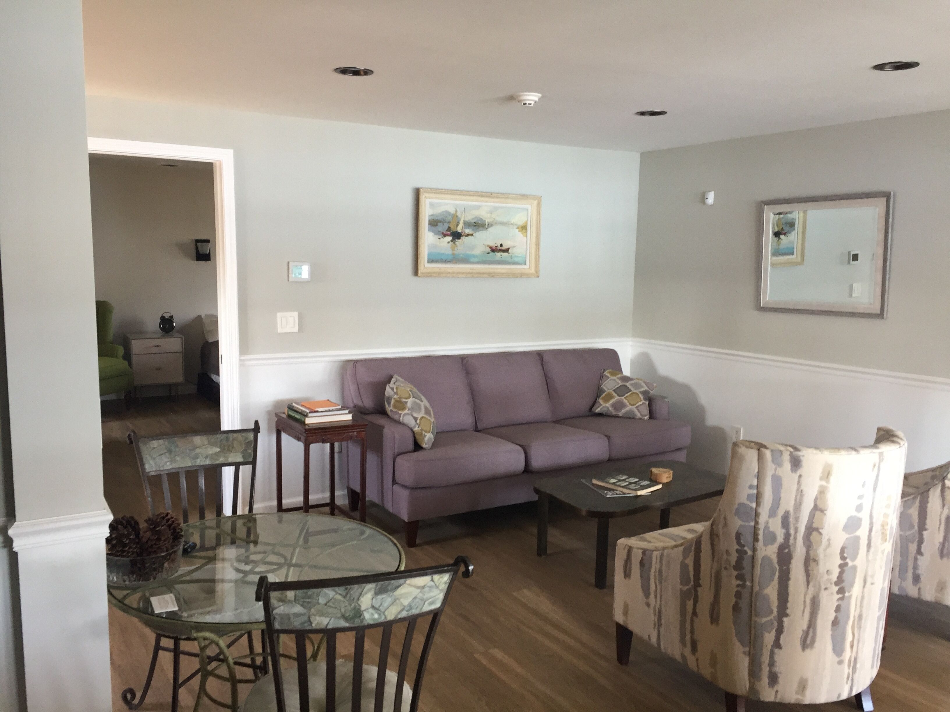 A living room with a glass-top dining table, a sofa, and a patterned armchair.