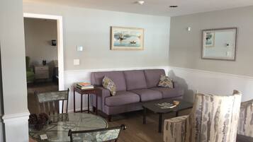 A living room with a glass-top dining table, a sofa, and a patterned armchair.