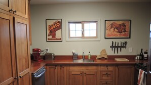 Una cocina con armarios de madera, una ventana, un lavamanos y dos cuadros en la pared.