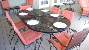 Un área de comedor al aire libre techada con una mesa redonda rodeada por seis sillas, cada una con un cojín.