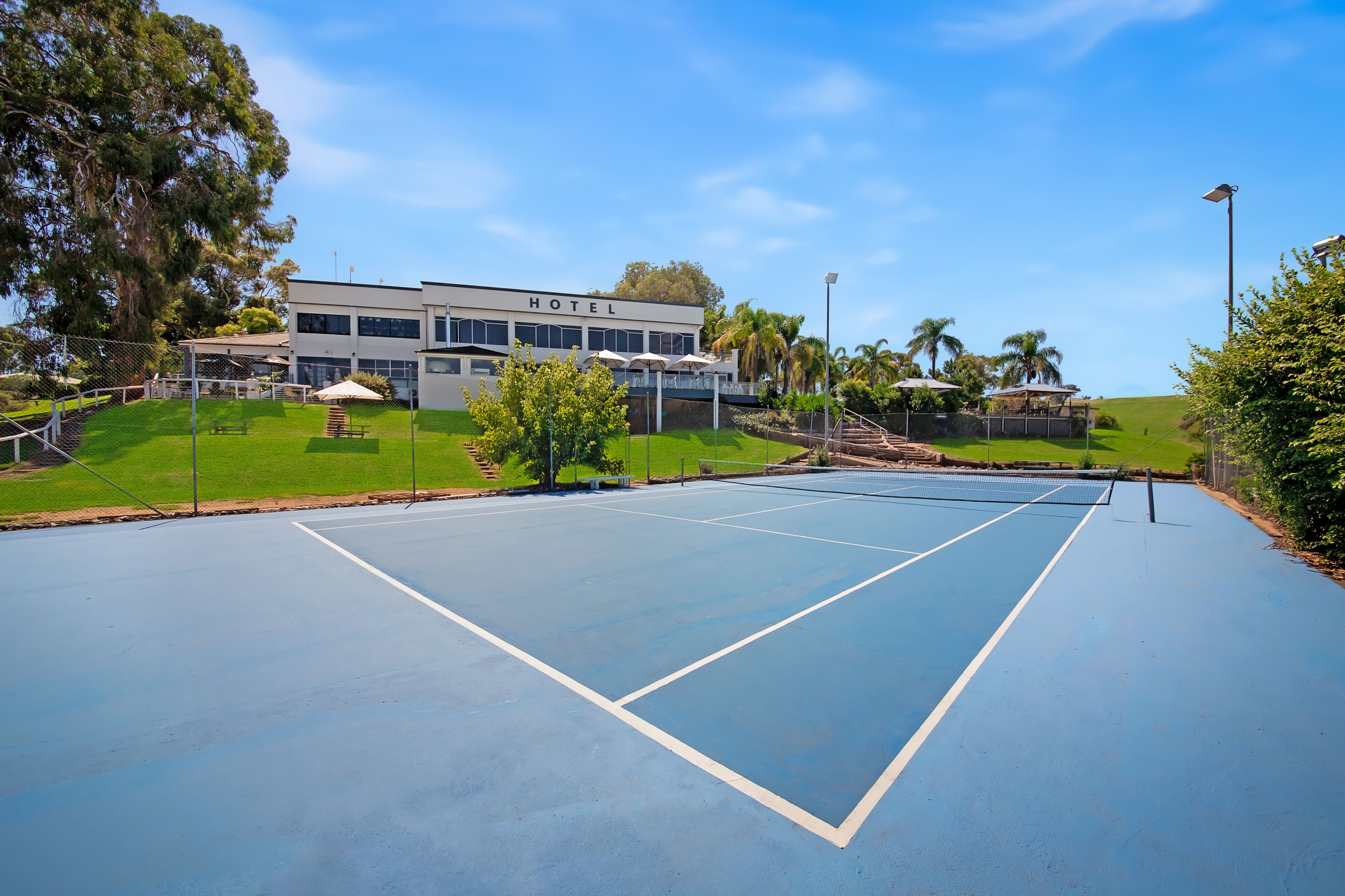 Un court de tennis avec un bâtiment d’hôtel en arrière-plan.