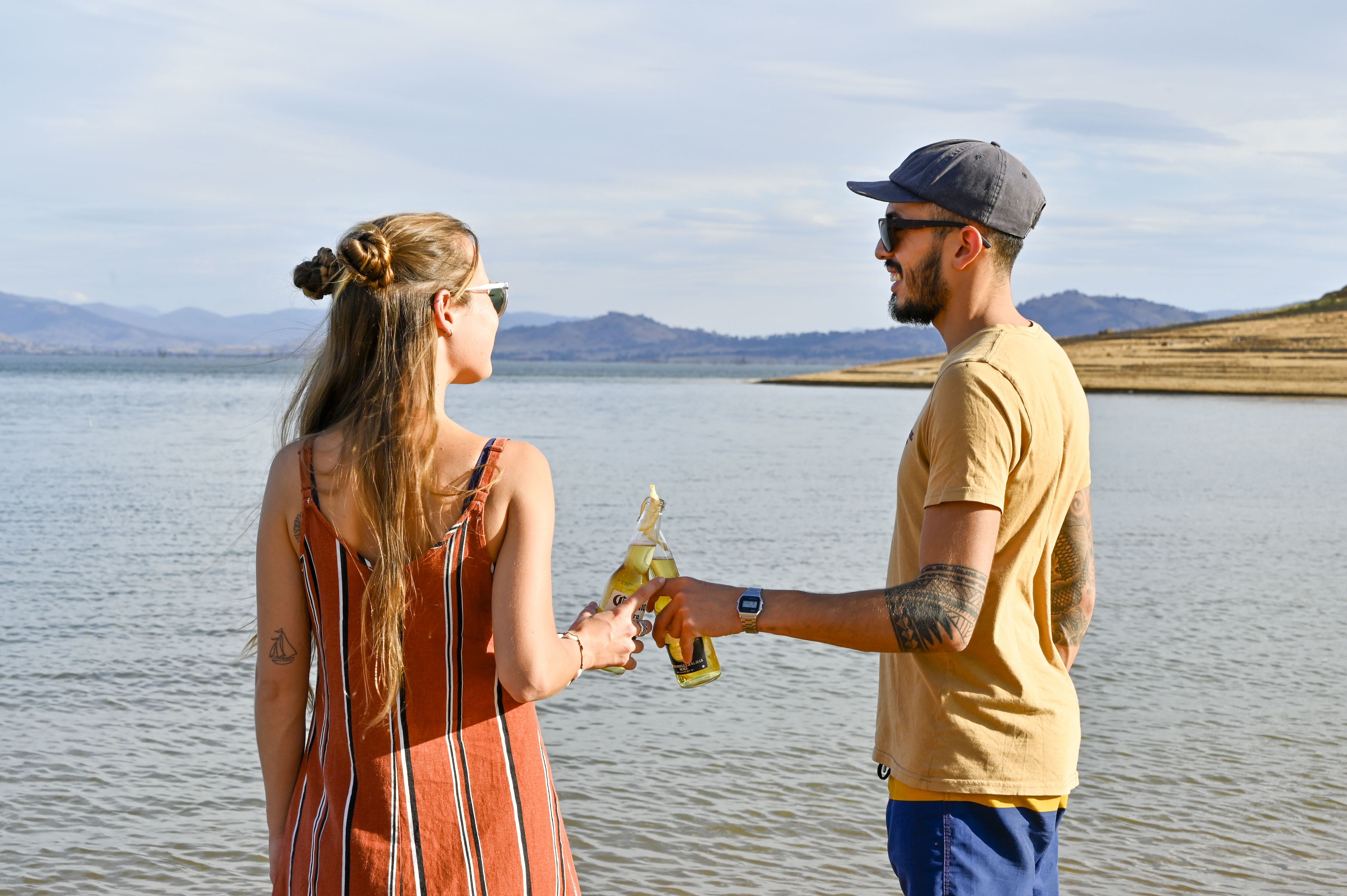 A couple by a lake with mountains in the background.