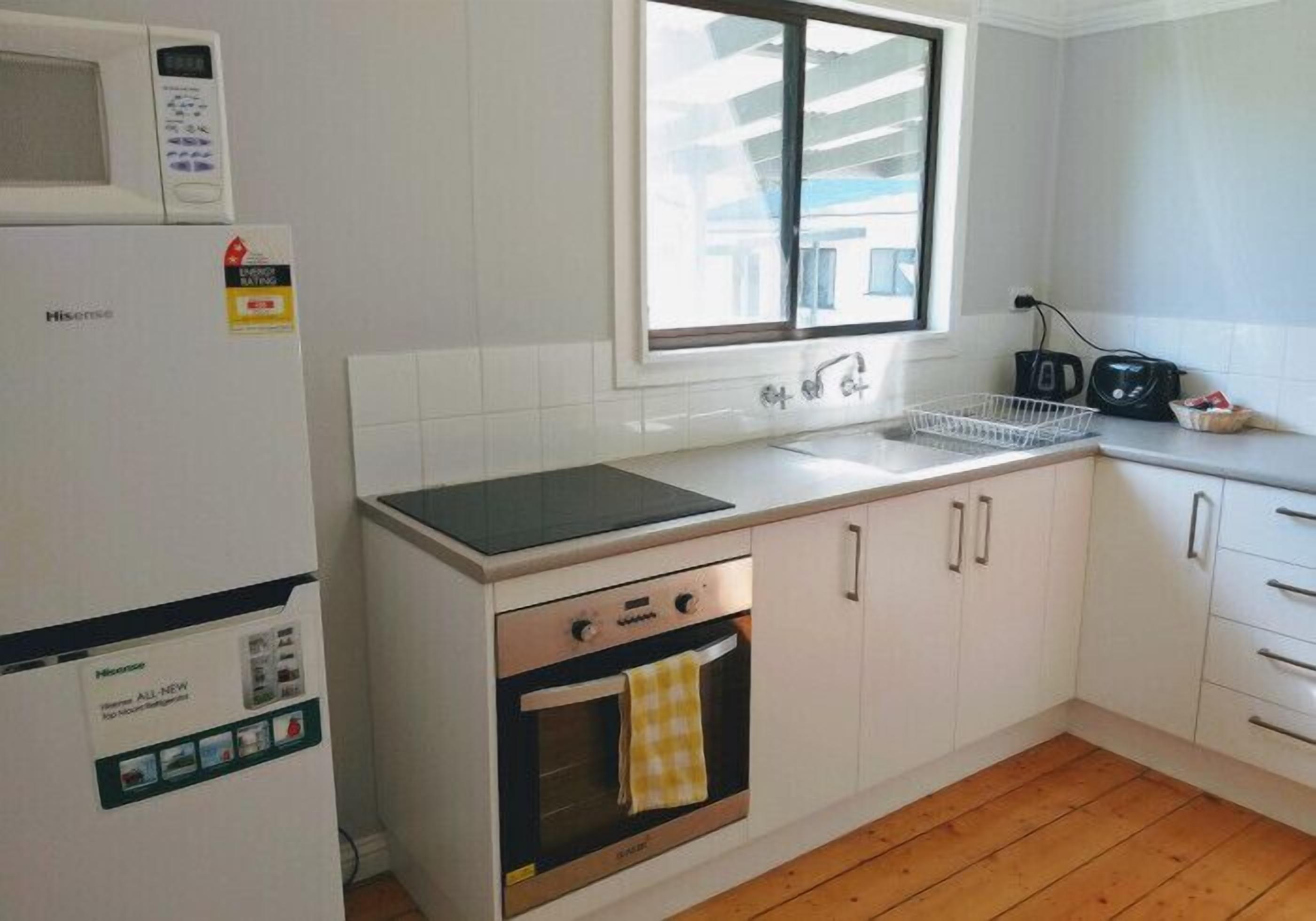 A compact kitchen with a microwave, oven, and sink.