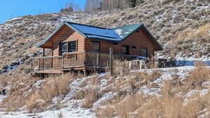 A wooden cabin with a balcony, surrounded by a snowy landscape and hills. - Peaceful Cabin for Two - Stunning Mountain Views - Wildlife Viewing (Gardiner)