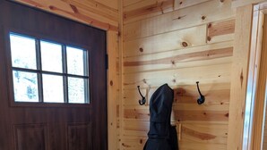 A wooden door with a window, a coat hanging on a hook, and a doorbell. - Peaceful Cabin for Two - Stunning Mountain Views - Wildlife Viewing (Gardiner)