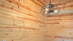 A wooden interior with a dining table set for two, chairs, and a hanging light fixture. - Peaceful Cabin for Two - Stunning Mountain Views - Wildlife Viewing (Gardiner)