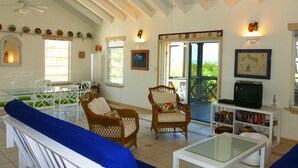 A spacious living room with a high ceiling, a glass coffee table, wicker chairs, a sofa, and a bookshelf. - Chill Out, Relax And Reconnect In A Sweet Cottage By The Beach (Whitby)