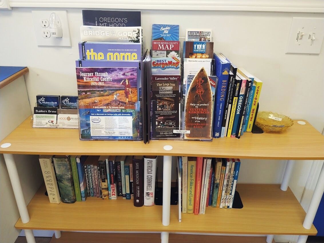 A bookshelf with various books and magazines, including travel guides and maps.