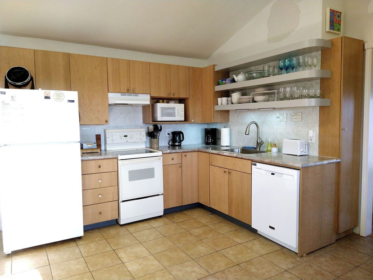 A modern kitchen with wooden cabinets, a white refrigerator, a microwave, a stove, and a dishwasher.