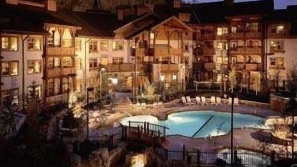Un hotel su più piani con area piscina, circondato da alberi e un paesaggio collinare.