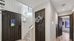 A hallway with two dark wooden doors, a staircase, and a decorative wreath. - Woodlands 31: Pet Friendly, On Sierra Star Golf Co (Mammoth Lakes)