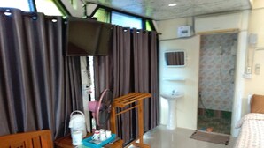 A hotel room with a bed, a wooden chair, a small table with toiletries, a TV mounted on the wall, a sink, and a shower area. - Phakdeehome Viewmorg (Khao Kho)