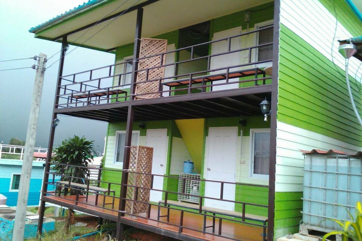 Un bâtiment à deux étages doté d’un balcon, d’une citerne d’eau et d’une clôture en métal.