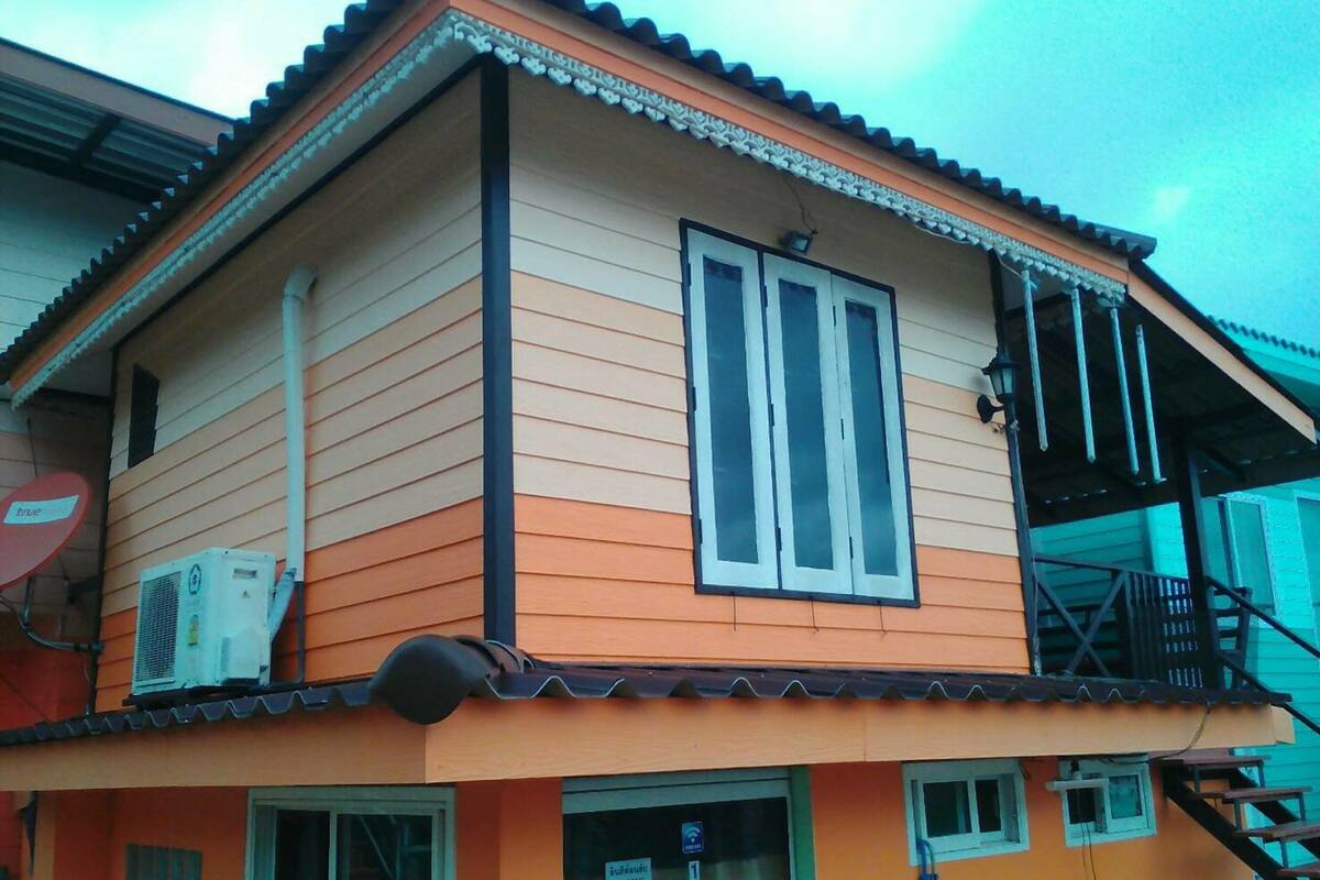 Un bâtiment à deux étages, doté d’un toit plat, d’un balcon au deuxième étage et d’une antenne parabolique sur le côté.