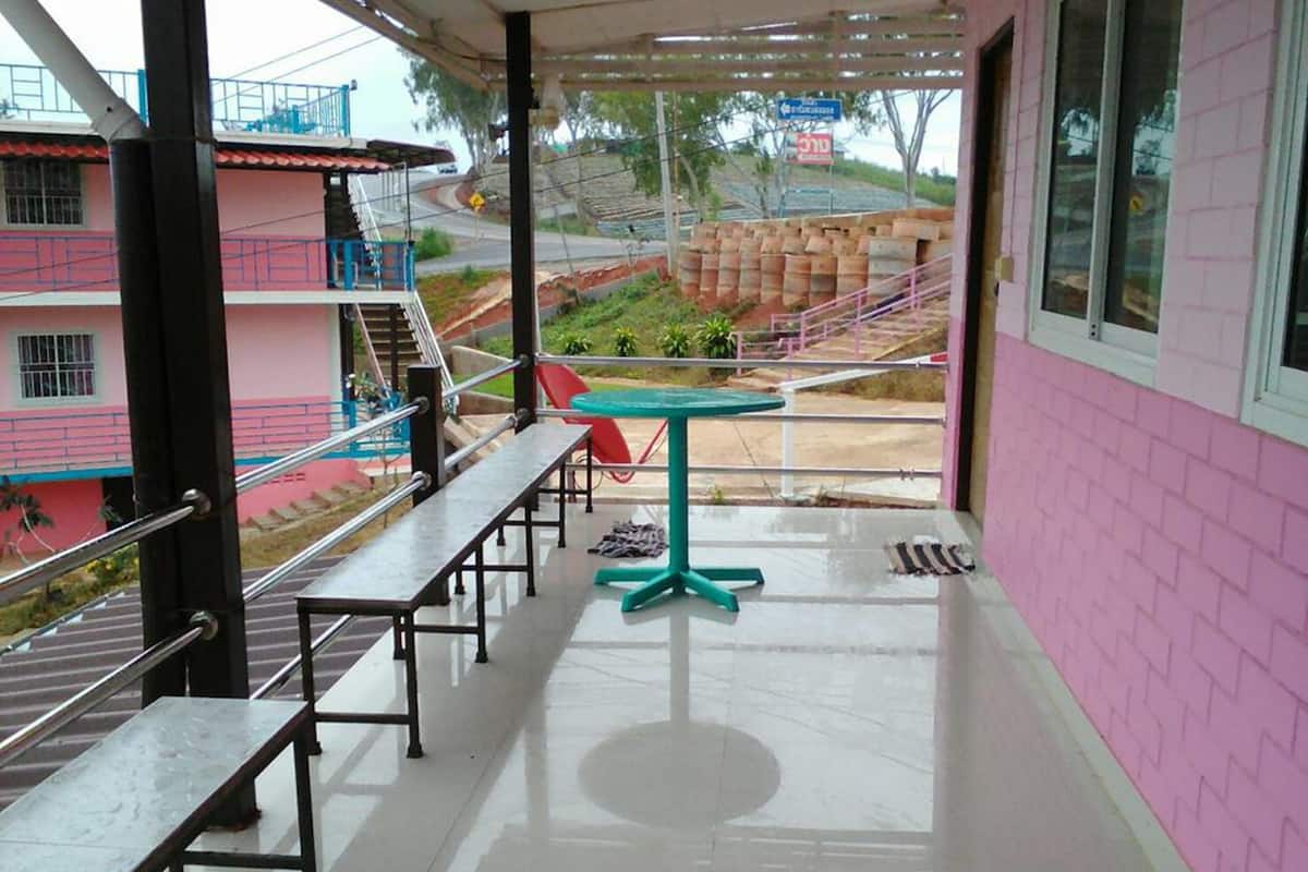 Un espace extérieur abrité, doté de bancs et d’une table, qui offre une vue sur une route et un paysage vallonné.