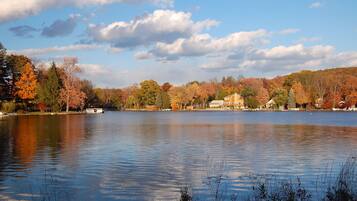 A lake with autumn foliage, a house, and a boat.