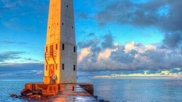 Un faro su un molo, cielo sereno e mare calmo.