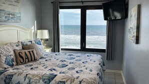 Una camera da letto con un letto, una TV, una finestra vista mare e un quadro appeso al muro.