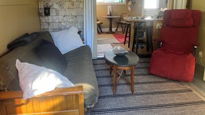 Ein gemütliches Wohnzimmer mit einem Holzsofa, einem roten Sessel und einem gemusterten Teppich.