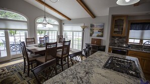 A kitchen with a marble island, wooden chairs, and a dining table.