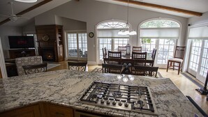 A kitchen with a large island, a dining area with a table and chairs, and a TV in the background.