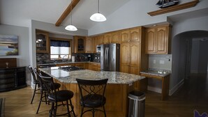 A spacious kitchen with granite countertops, wooden cabinets, and a stainless steel refrigerator.