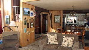 Ein gemütliches Wohnzimmer mit einer Couch, einem Sessel und einem Essbereich mit Holzmöbeln.