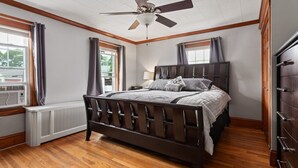 Un dormitorio con una cama de madera, un ventilador de techo y una ventana con cortinas.