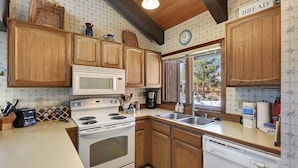 A kitchen with wooden cabinets, a white stove, a microwave, and a dishwasher. - Sunrise 3: Pet Friendly, Mountain Views (Mammoth Lakes)