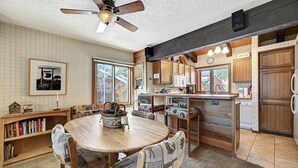 A cozy kitchen with wooden cabinets, a dining area with a round table and chairs, and a ceiling fan. - Sunrise 3: Pet Friendly, Mountain Views (Mammoth Lakes)