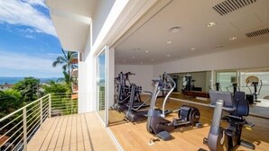 A gym with exercise equipment on a balcony overlooking a scenic view. - Luxury Los Muertos Beach penthouse, infinity pool & Jacuzzi, central located  (Puerto Vallarta)