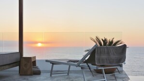 A sunlit terrace with a lounge chair and a potted plant, overlooking the sea at sunset. - Luxury Los Muertos Beach penthouse, infinity pool & Jacuzzi, central located  (Puerto Vallarta)